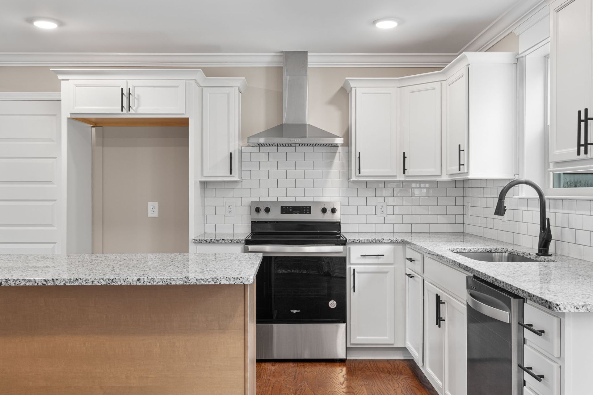 A kitchen with white cabinets , granite counter tops , stainless steel appliances and a stove.