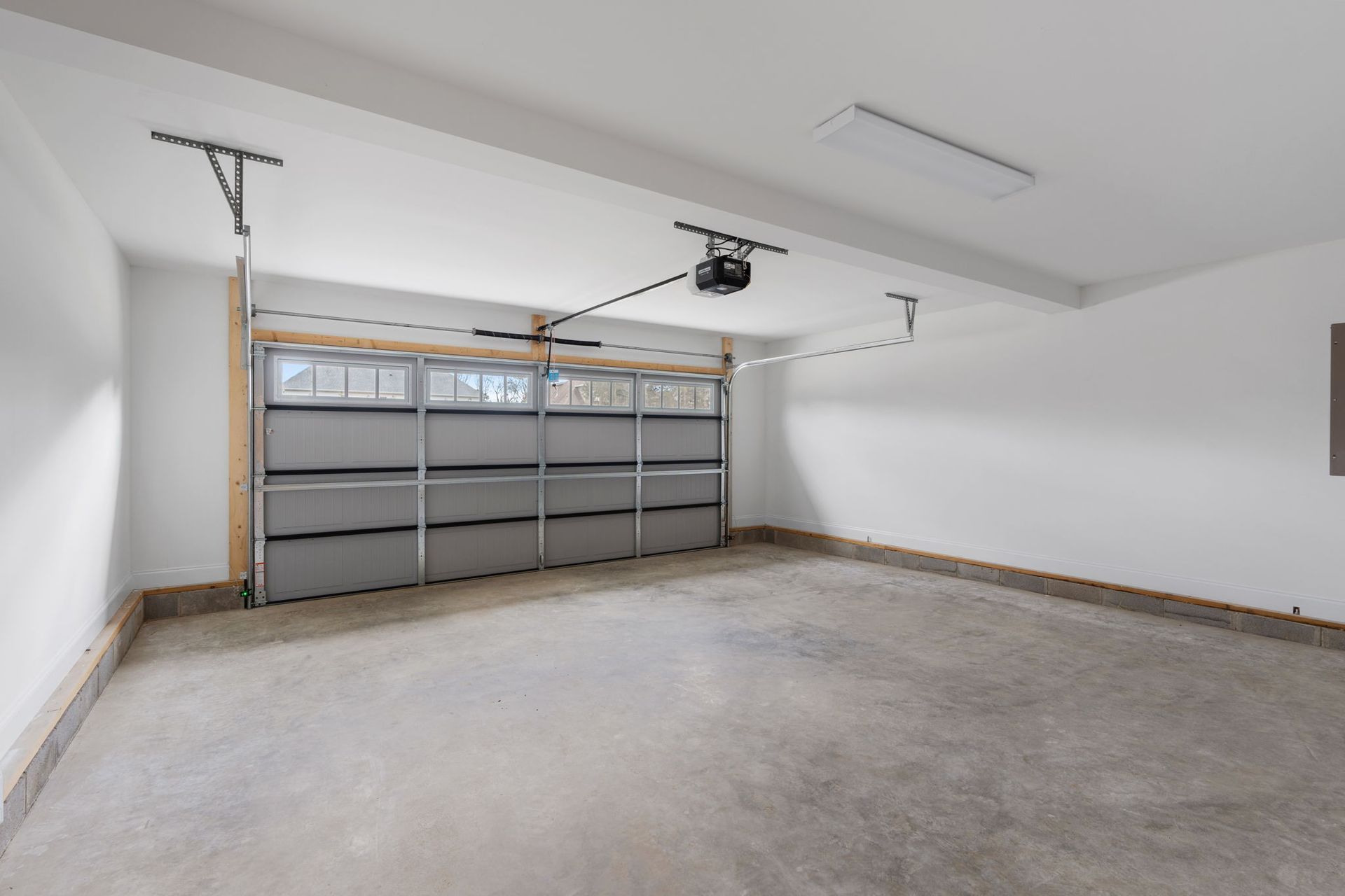 An empty garage with a garage door open and a ceiling fan.