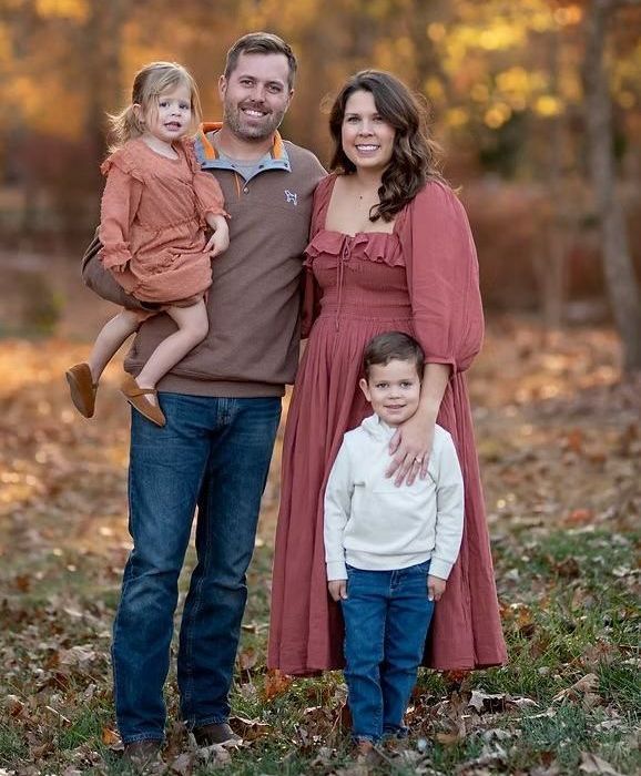 A family is posing for a picture in the woods.