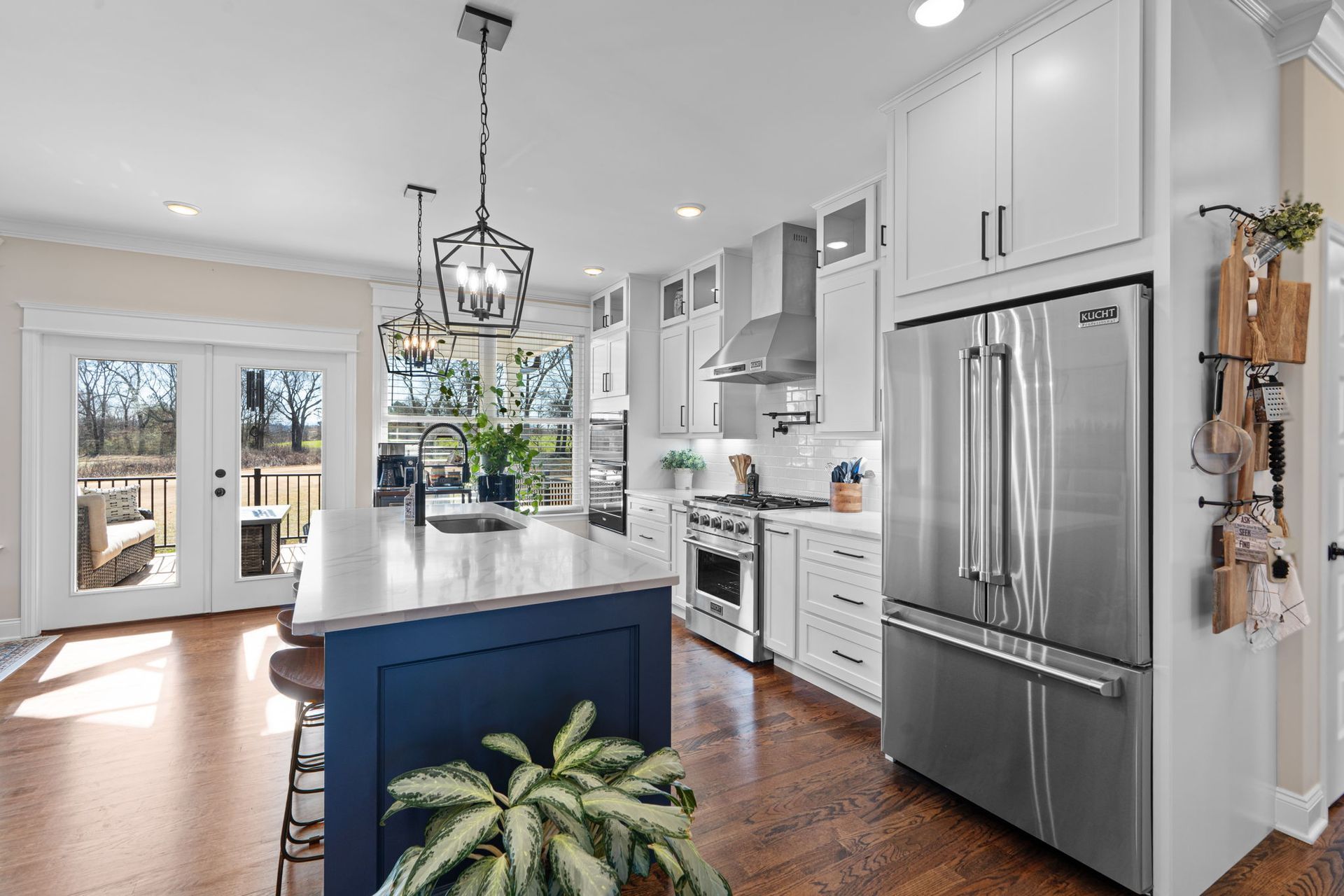 A kitchen with white cabinets and stainless steel appliances and a blue island.