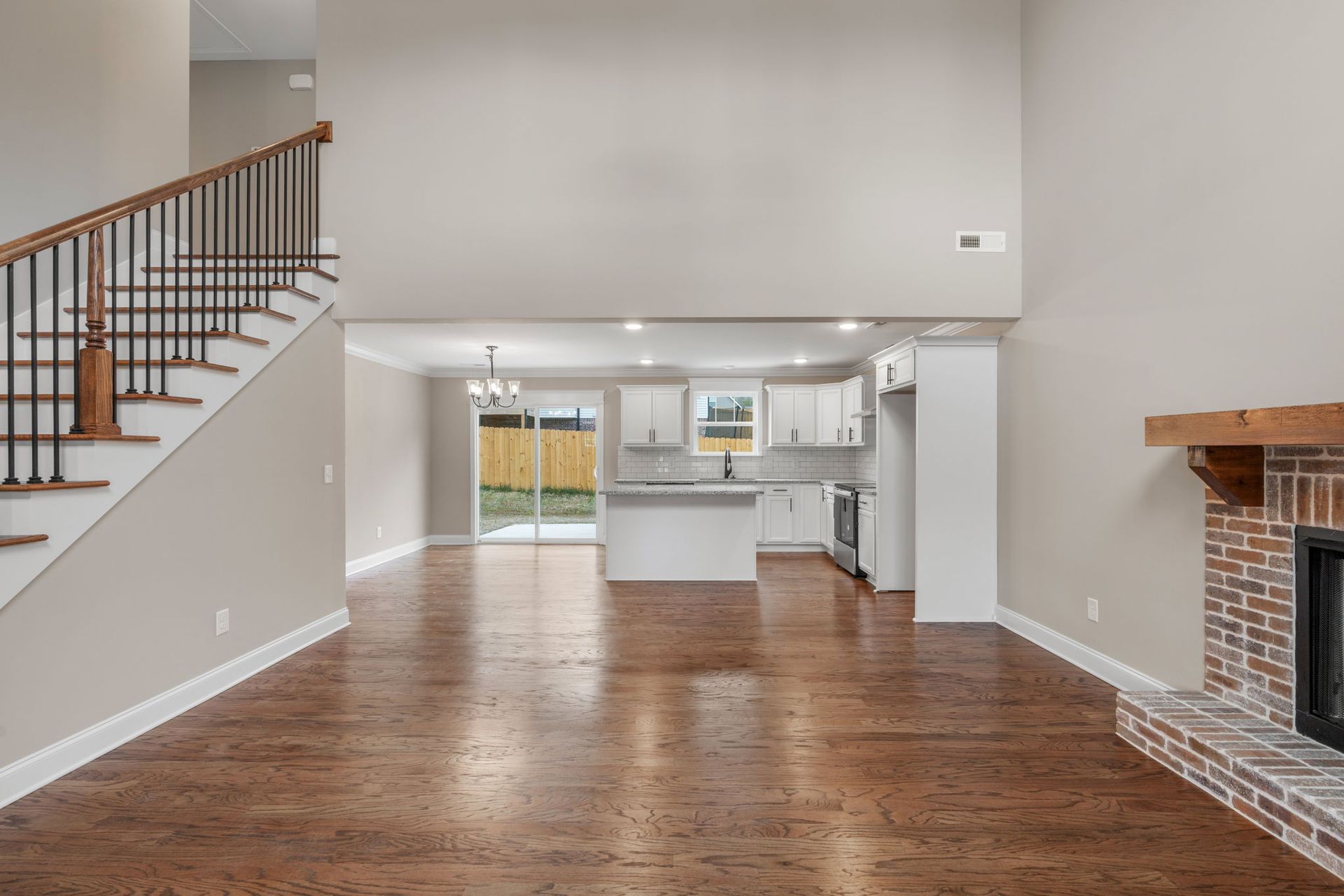 An empty living room with hardwood floors , stairs , and a fireplace.