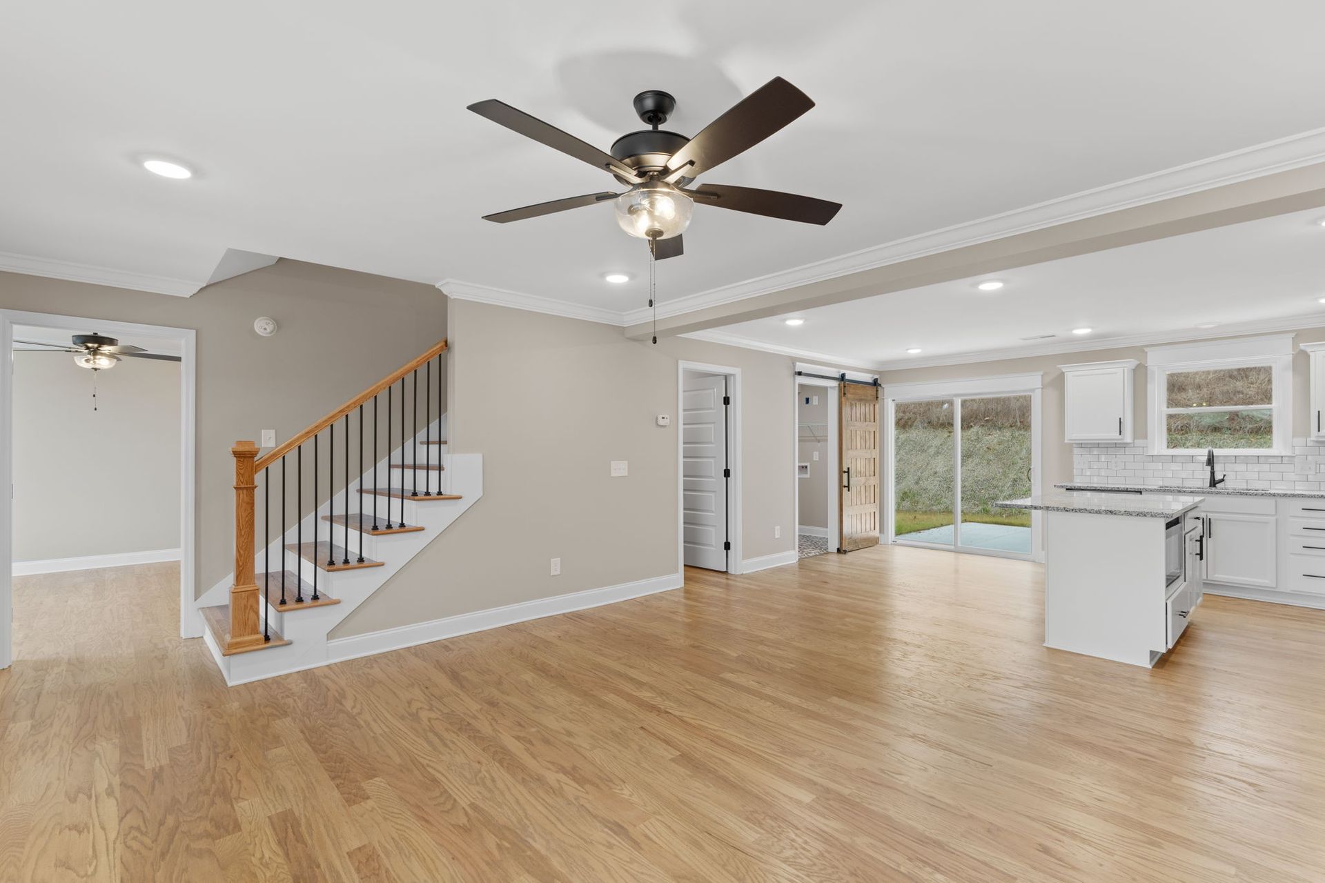A living room with hardwood floors and a ceiling fan.