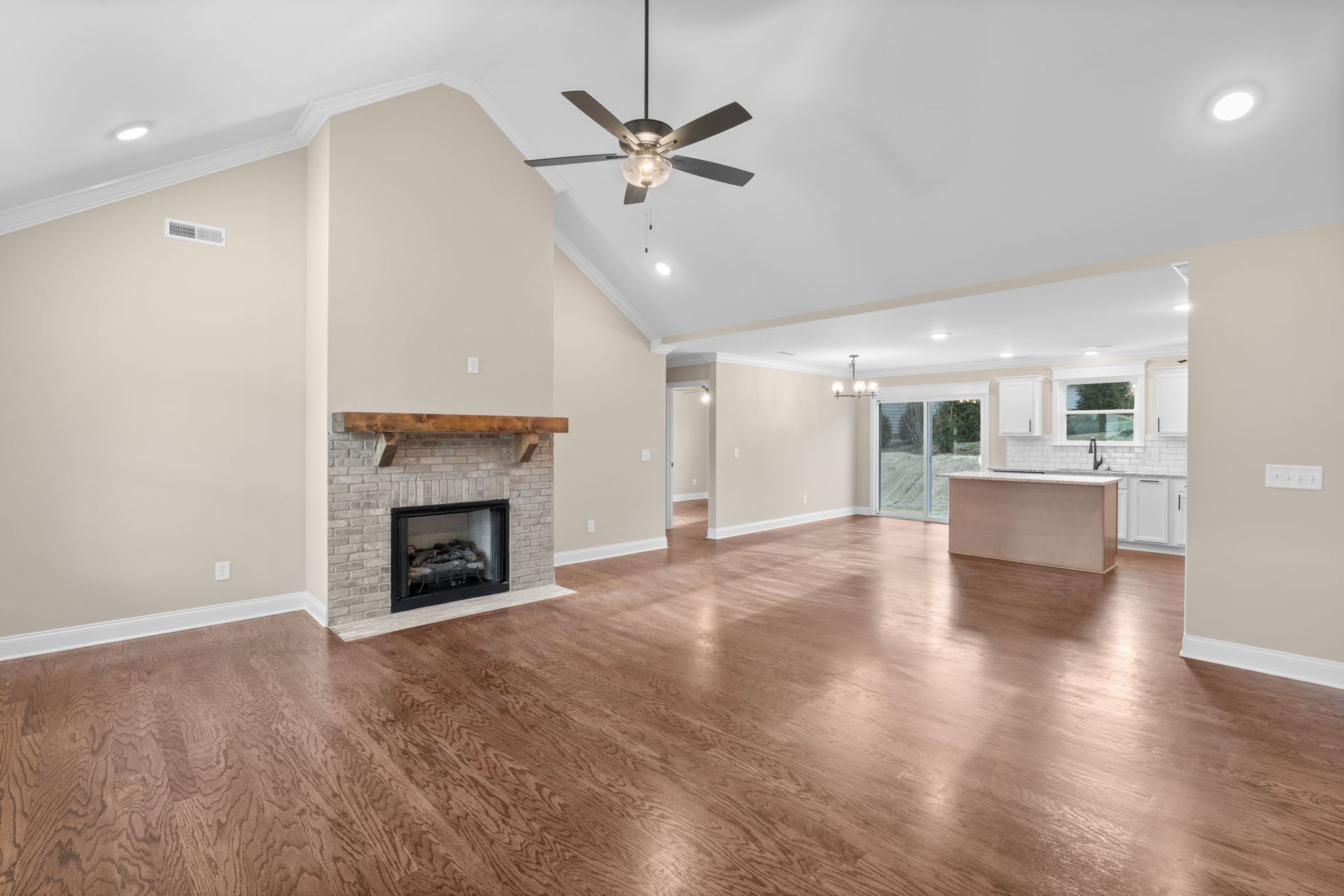 An empty living room with a fireplace and a ceiling fan.