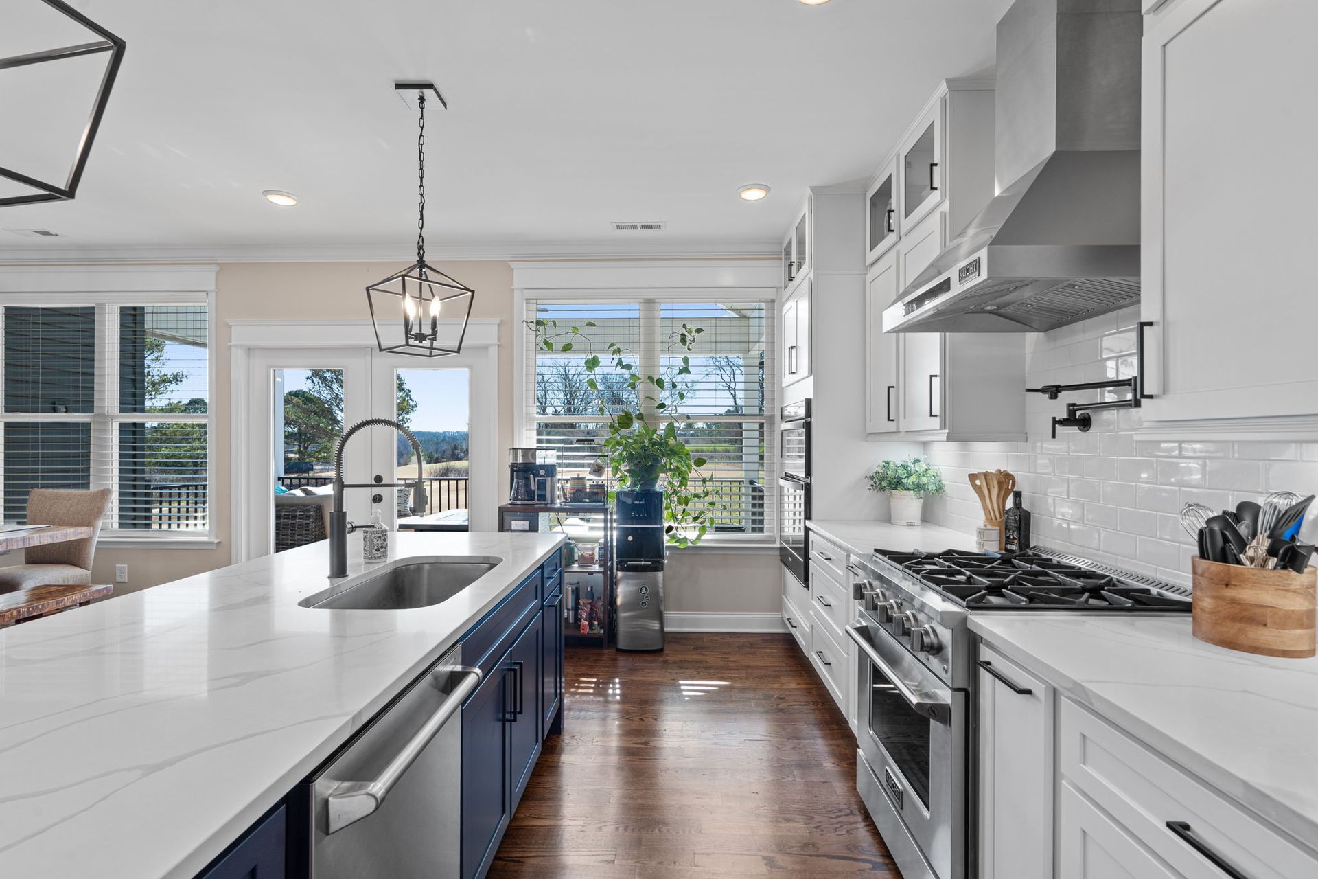 A kitchen with white cabinets , stainless steel appliances , and a large island.