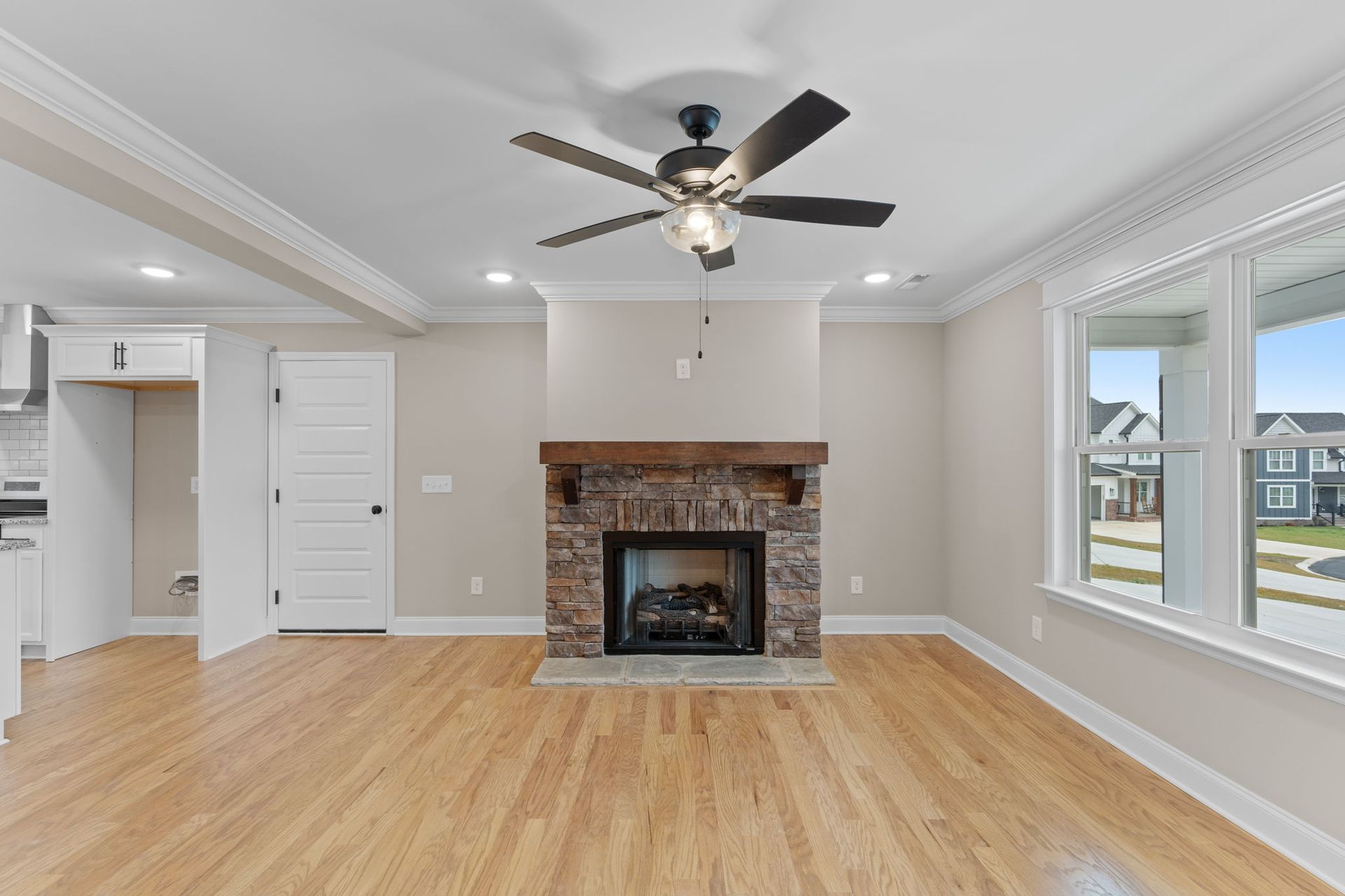An empty living room with a fireplace and ceiling fan.