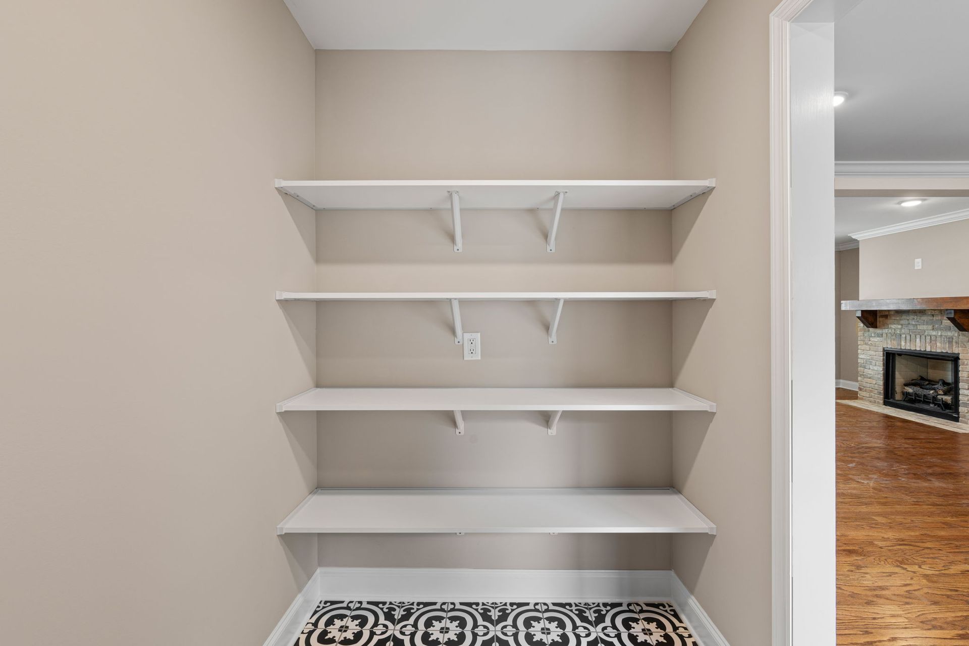 A room with empty shelves and a fireplace in the background.