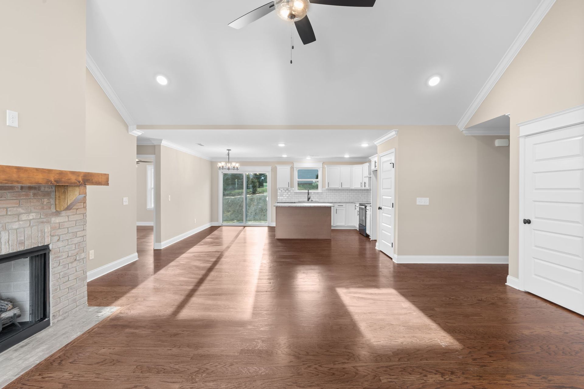 A living room with hardwood floors , a fireplace and a ceiling fan.
