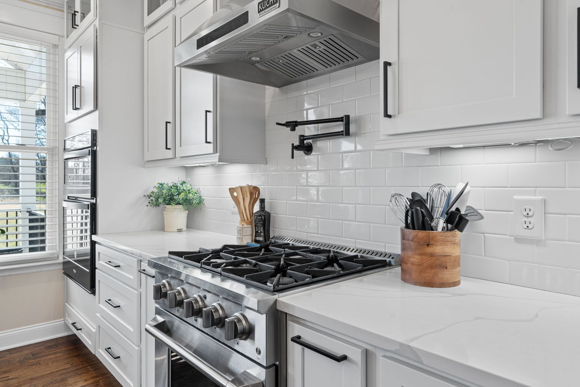 A kitchen with white cabinets , stainless steel appliances , and a stove top oven.