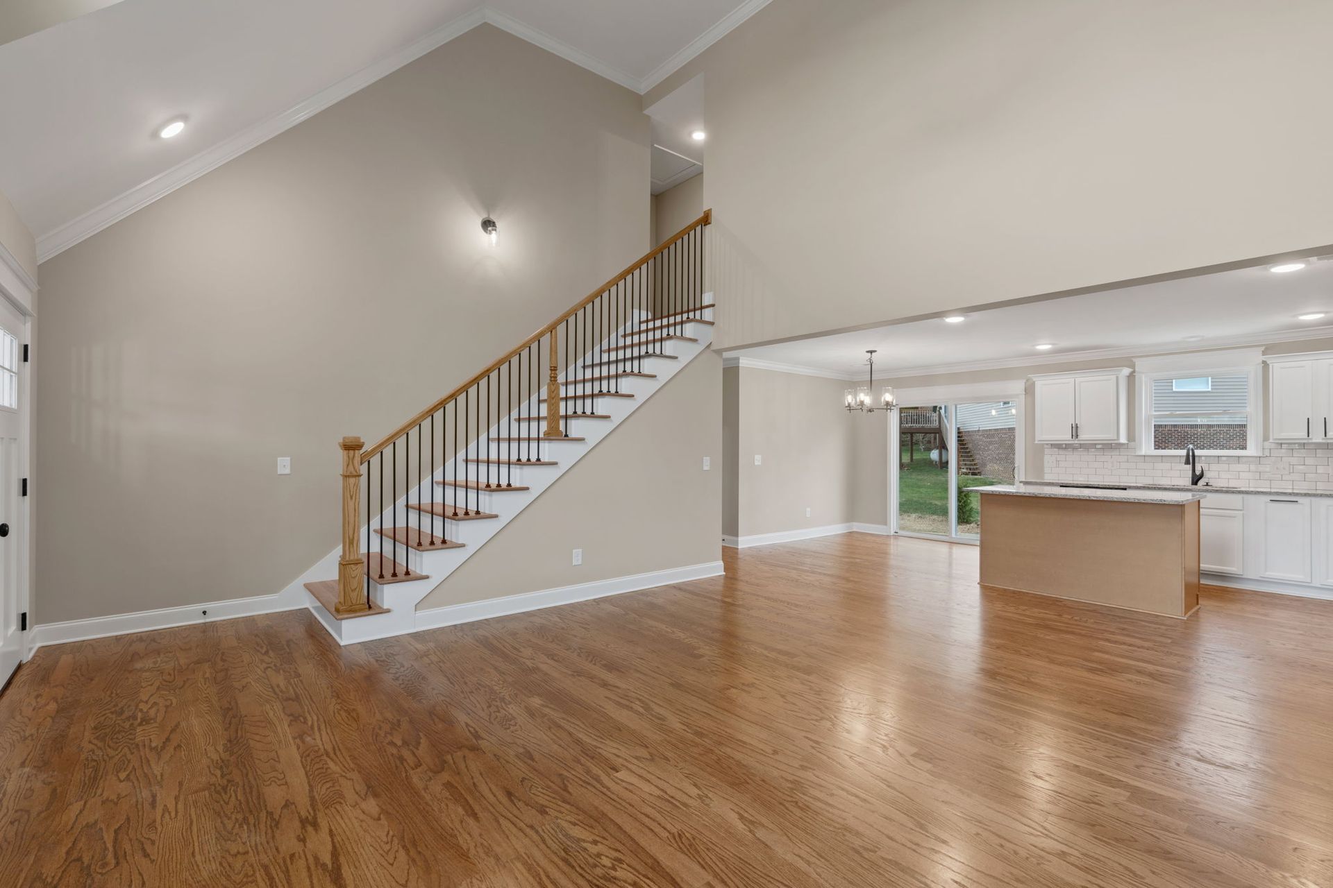 An empty living room with hardwood floors and stairs in a house.