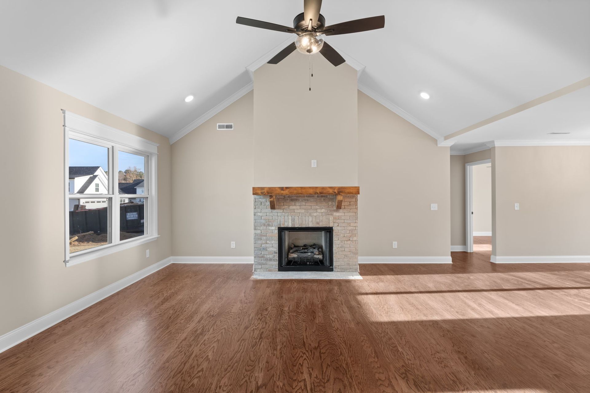 An empty living room with a fireplace and ceiling fan.