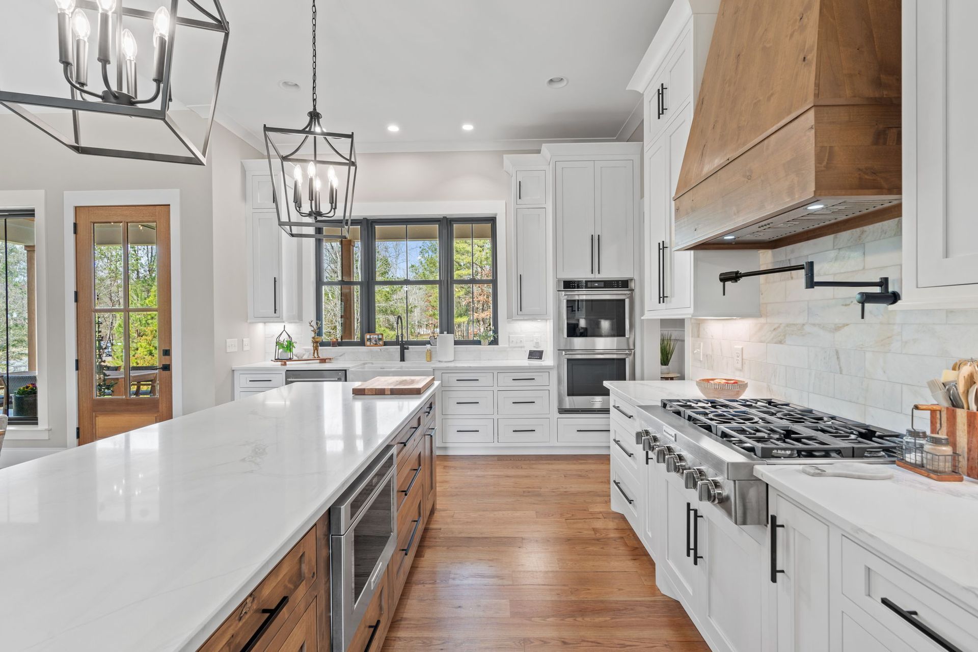 A kitchen with white cabinets , stainless steel appliances , and a large island.