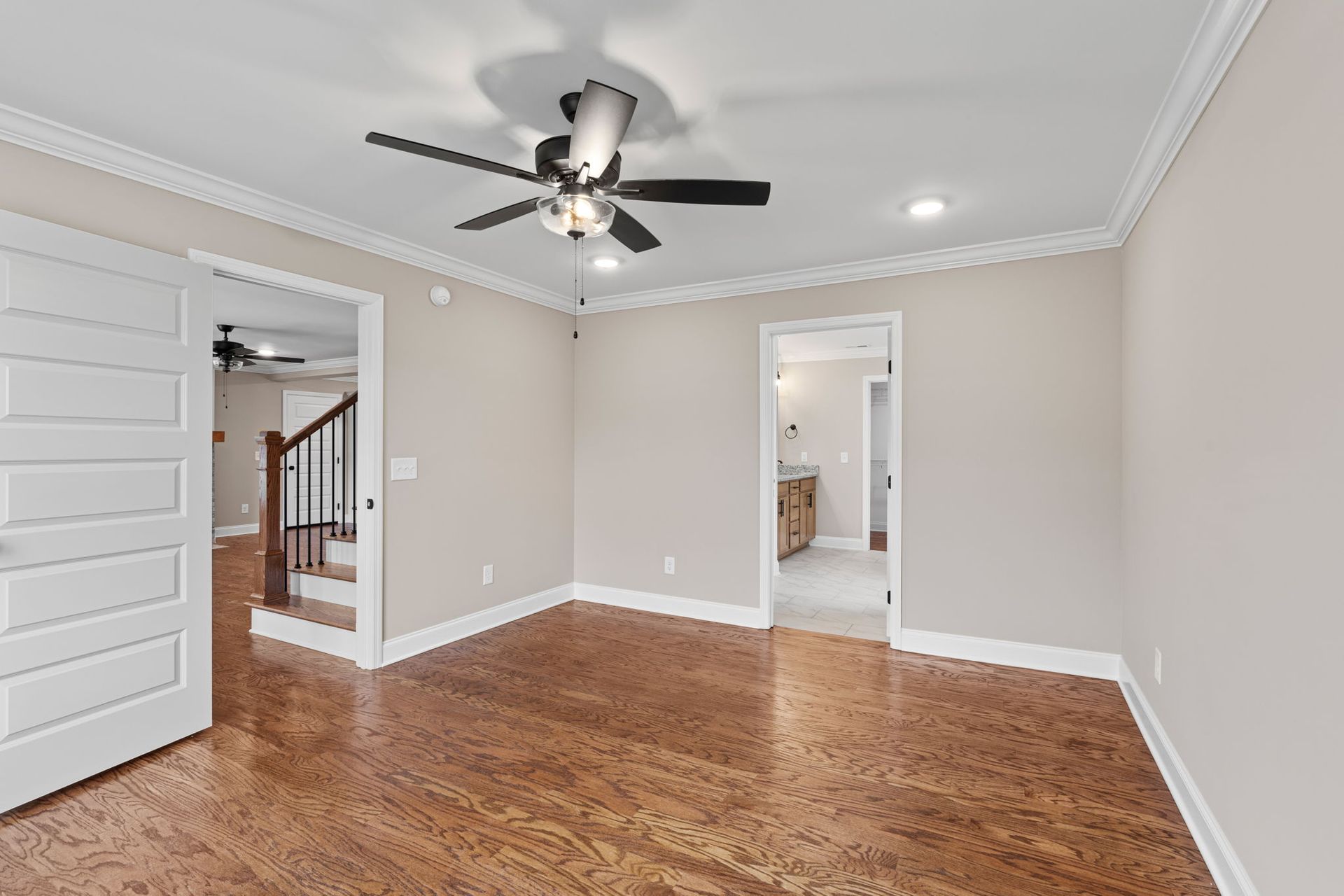 An empty living room with hardwood floors and a ceiling fan.