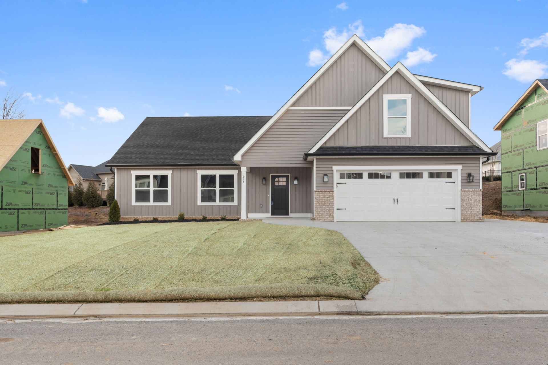 A house with a garage and a green house in the background