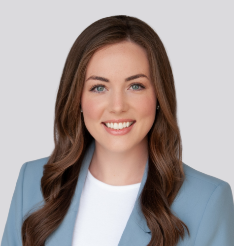 A woman in a blue jacket and white shirt is smiling for the camera.