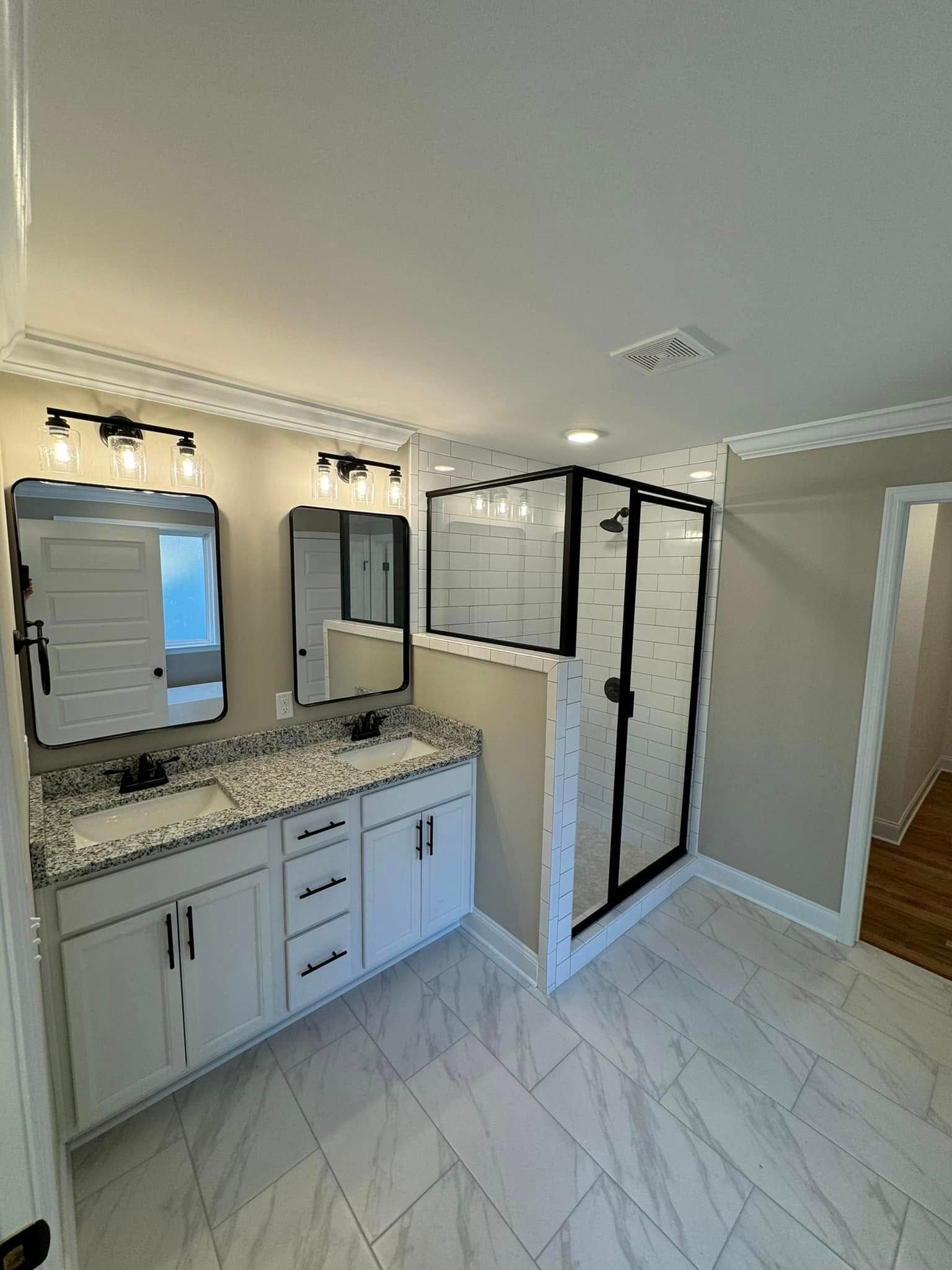A bathroom with two sinks and a walk in shower.
