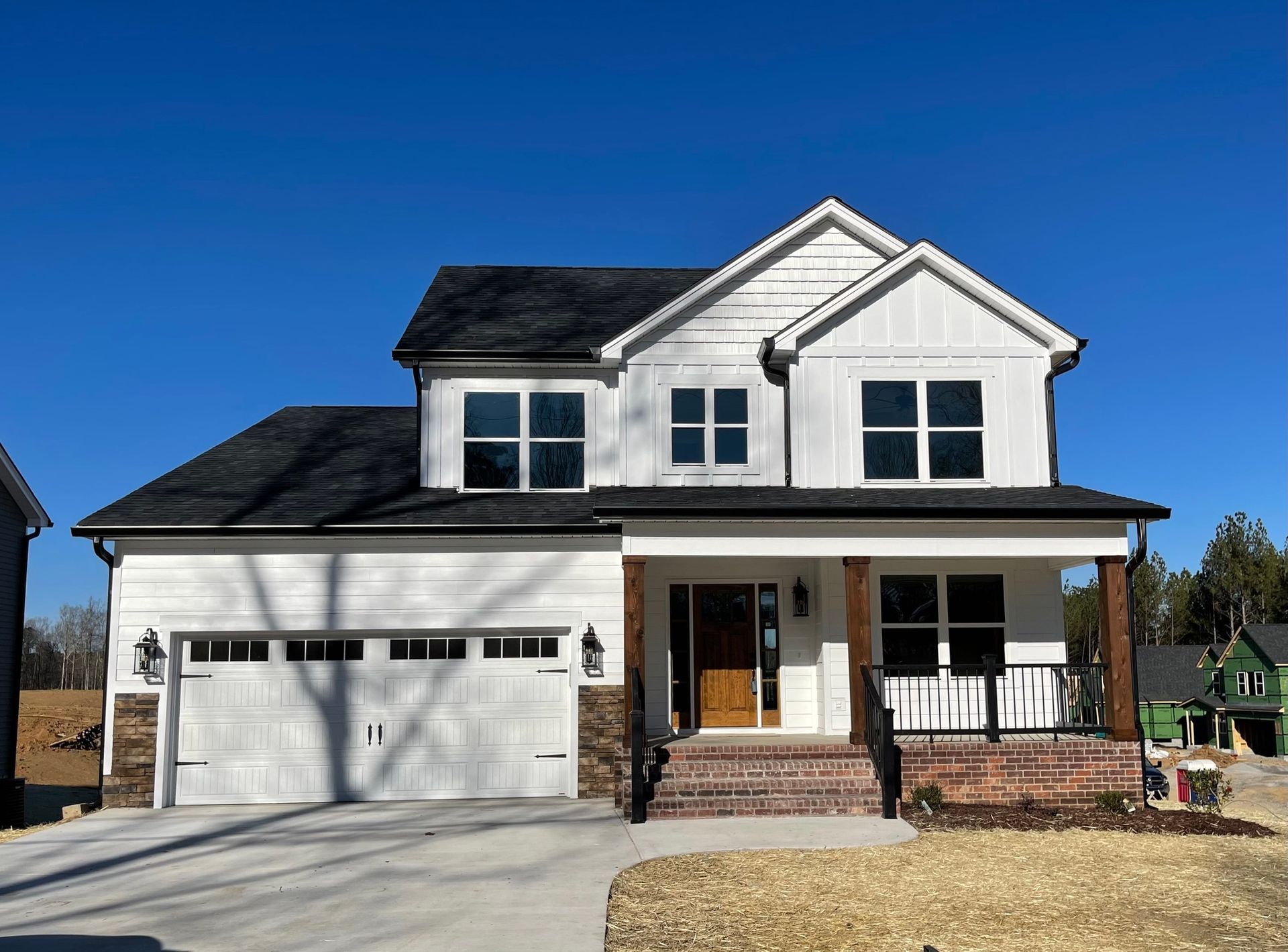 A large white house with a black roof and a large garage.