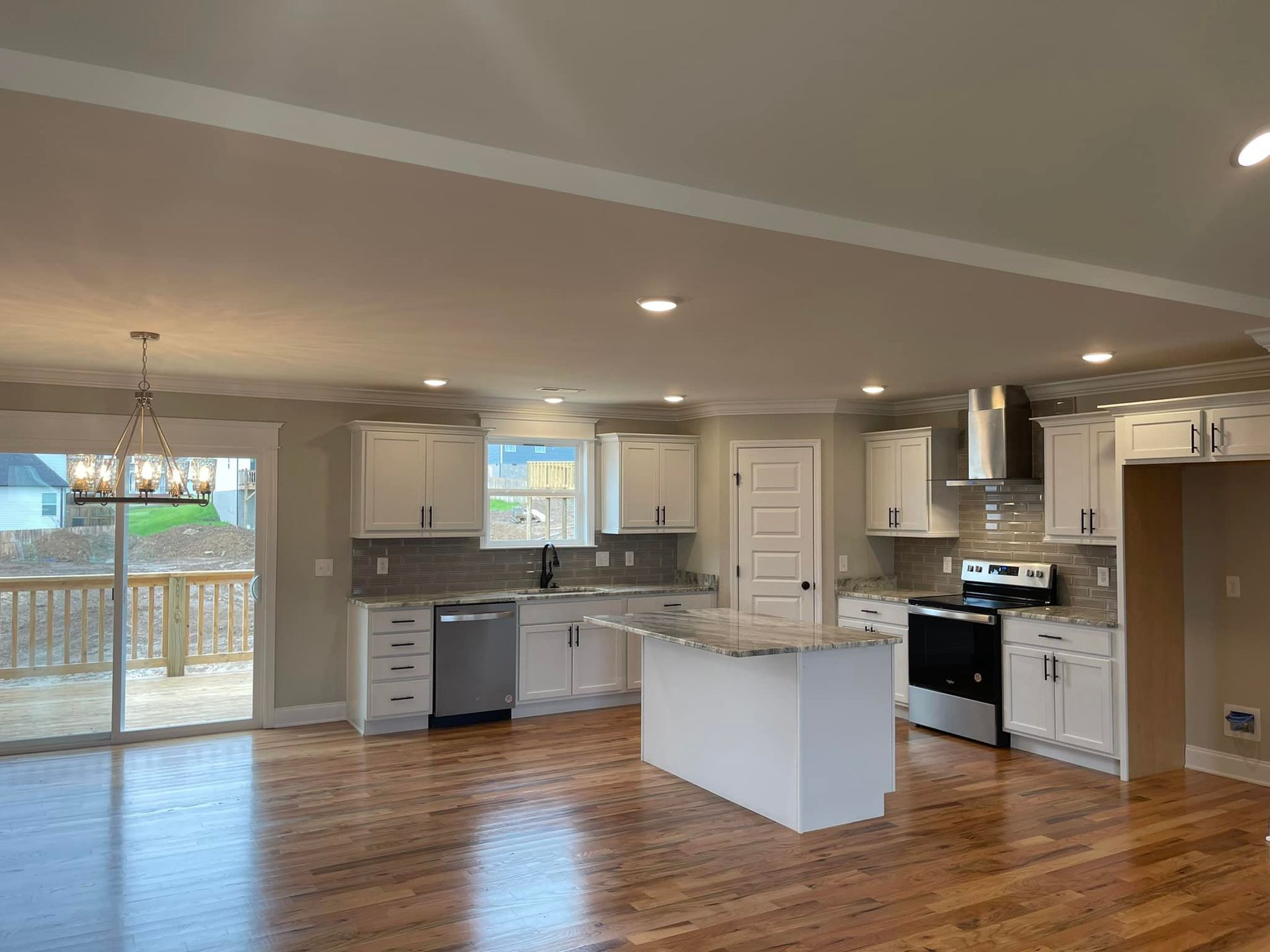 A kitchen with white cabinets , stainless steel appliances , a large island and hardwood floors.