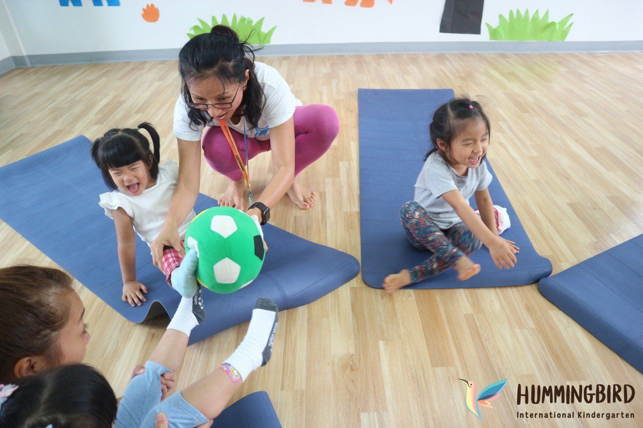 A group of children are playing with a soccer ball on yoga mats.