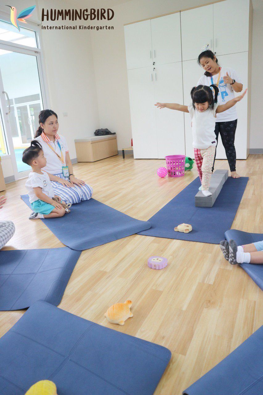 A group of children are sitting on yoga mats in a room.