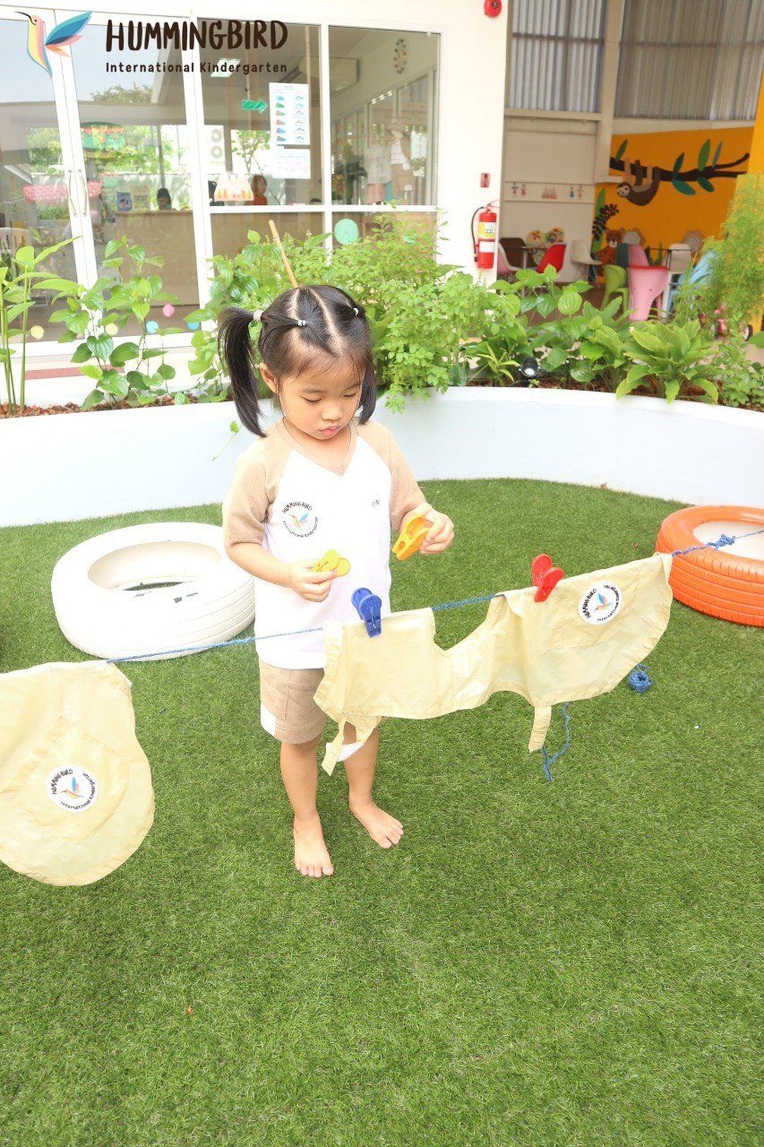 A little girl is standing on a lush green field playing with toys.