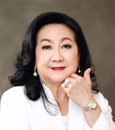 A woman wearing a white jacket and a watch is giving a thumbs up.