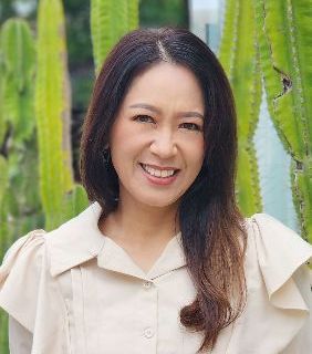 A woman in a white shirt and black vest is smiling for the camera.