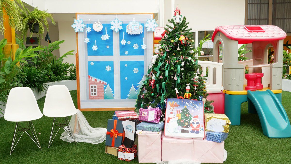 A christmas tree is sitting on top of a pile of presents in front of a playhouse.