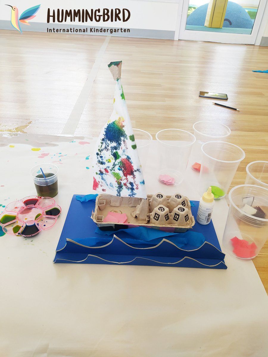 A sailboat made out of egg cartons is sitting on a table.