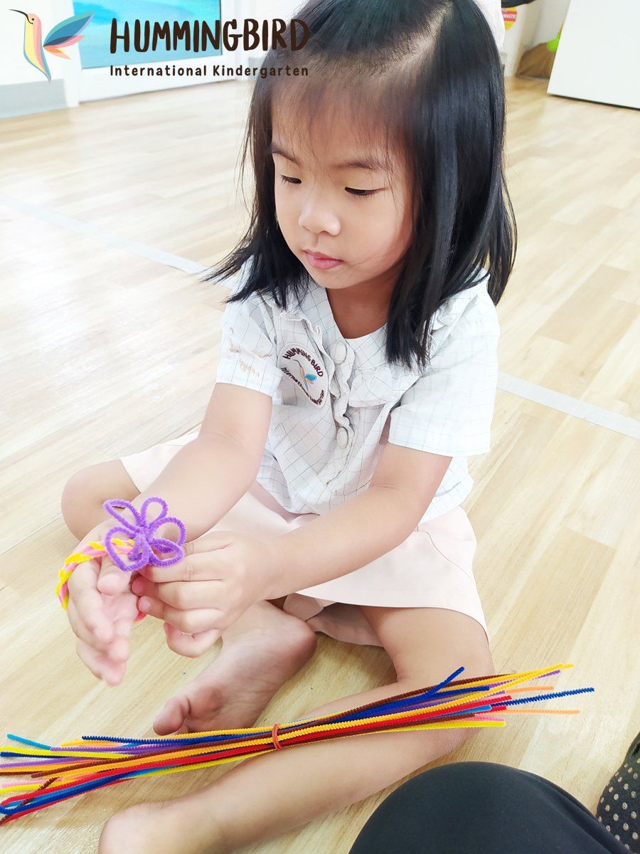 A little girl is sitting on the floor playing with straws.