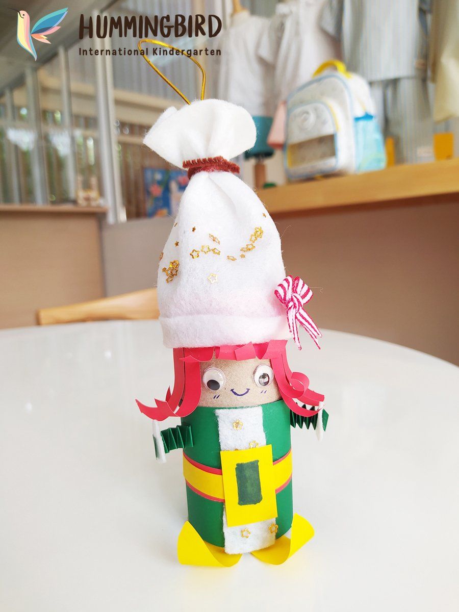 A doll made out of toilet paper rolls is sitting on a table.