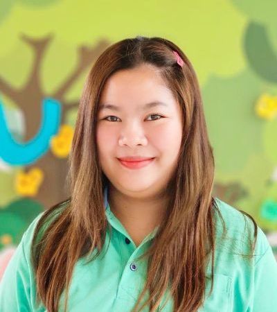 A woman in a green shirt is smiling for the camera.