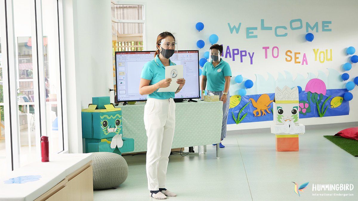 A woman wearing a mask is standing in front of a television in a room.