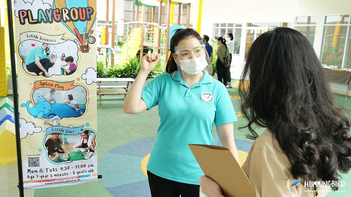 A woman wearing a mask is talking to another woman while holding a clipboard.