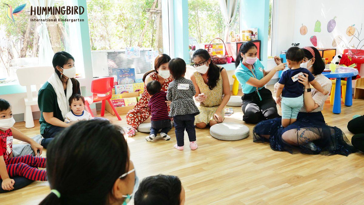 A group of people wearing face masks are sitting on the floor in a room.