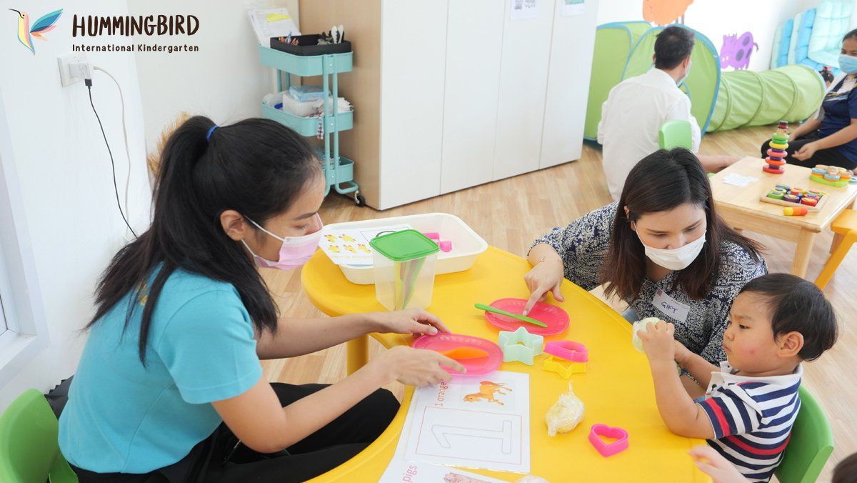 A group of people are sitting around a yellow table.