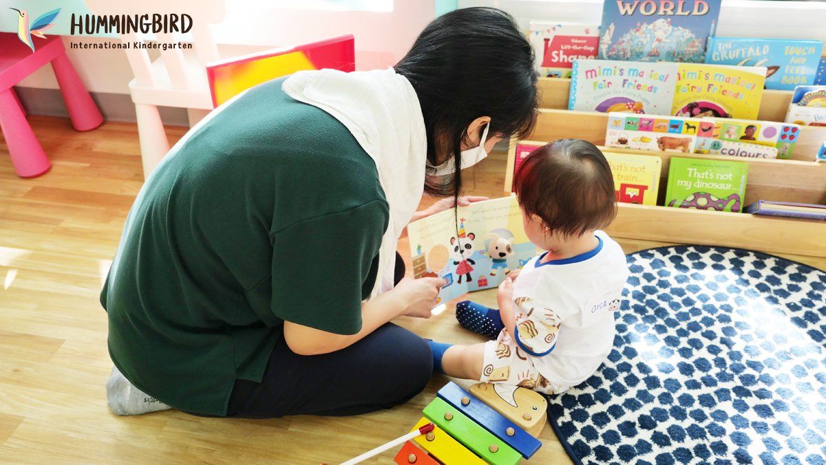 A woman is sitting on the floor reading a book to a baby.