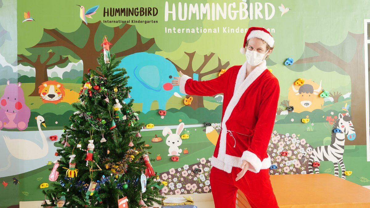 A man dressed as santa claus is standing next to a christmas tree.