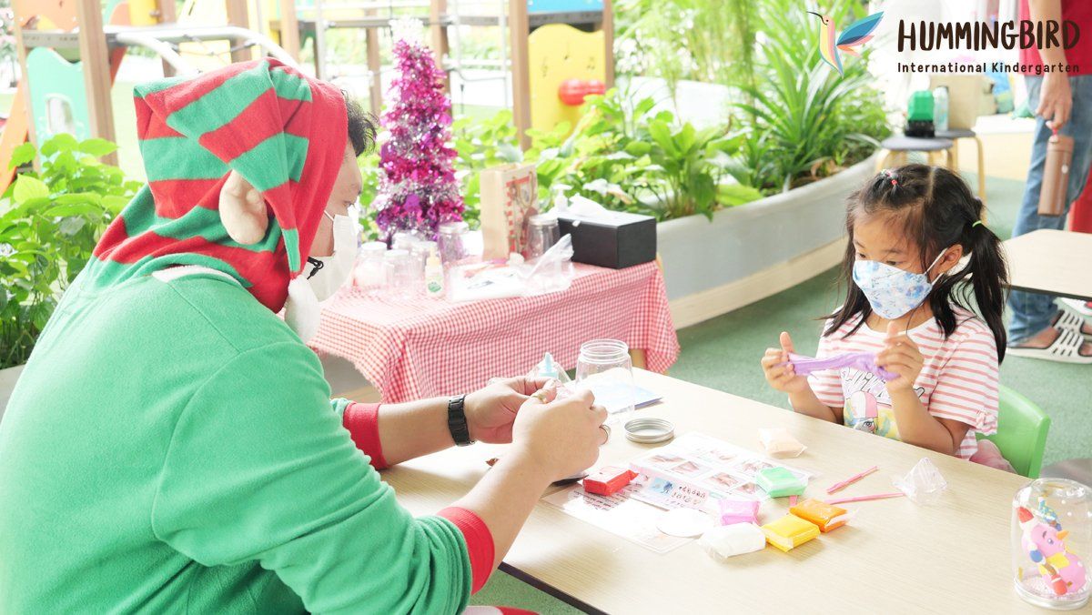 A woman is sitting at a table with a little girl wearing a mask.
