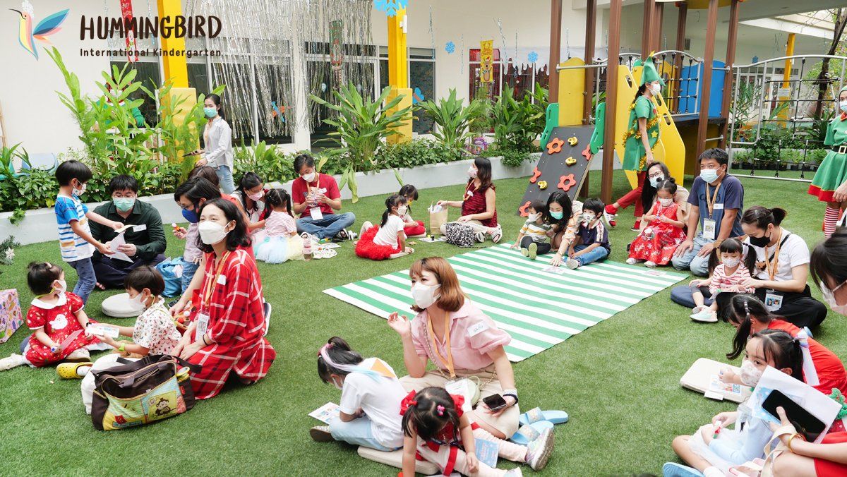 A group of people are sitting on the grass wearing masks.