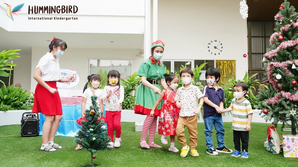 A group of children are standing in front of a christmas tree.