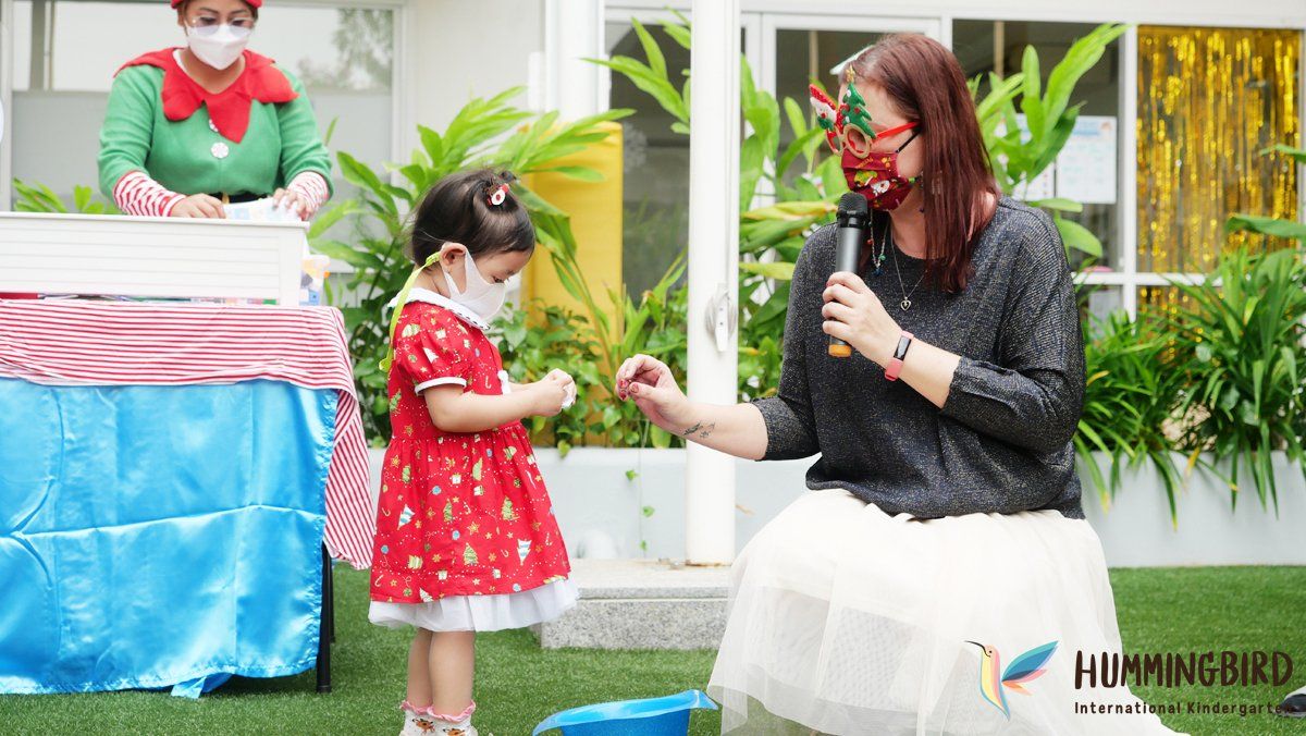 A woman is sitting next to a little girl wearing a mask and holding a microphone.