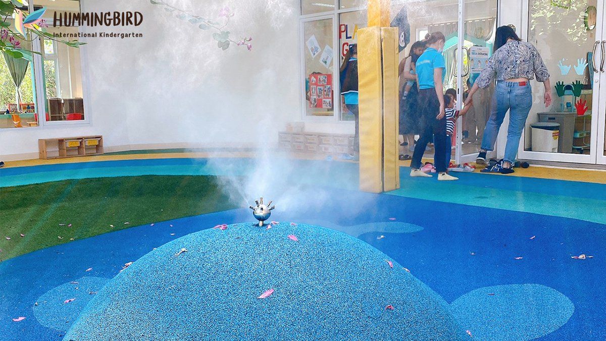 A group of people are standing around a sprinkler in a playground.