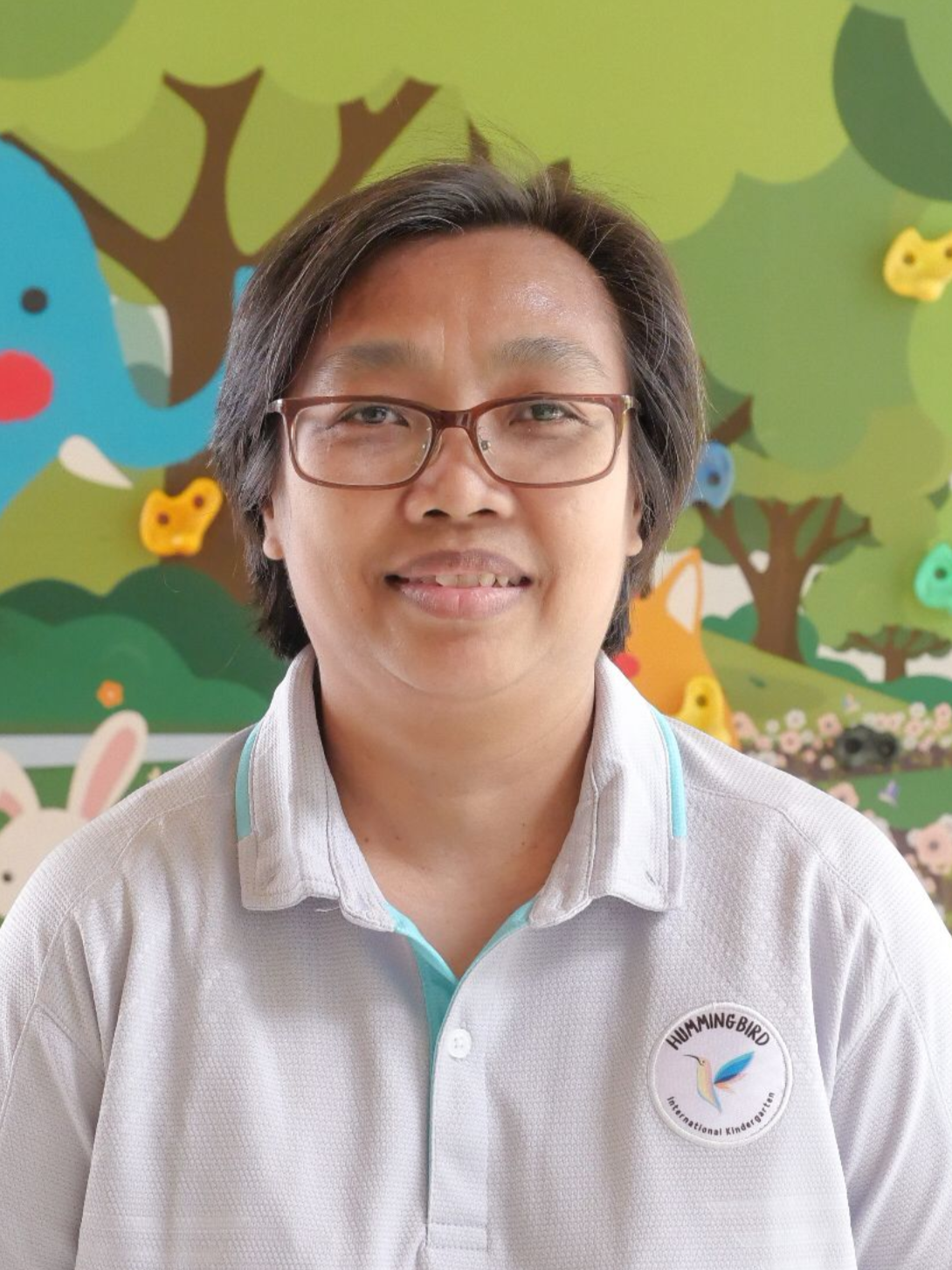 A woman wearing glasses and a lanyard is smiling for the camera.