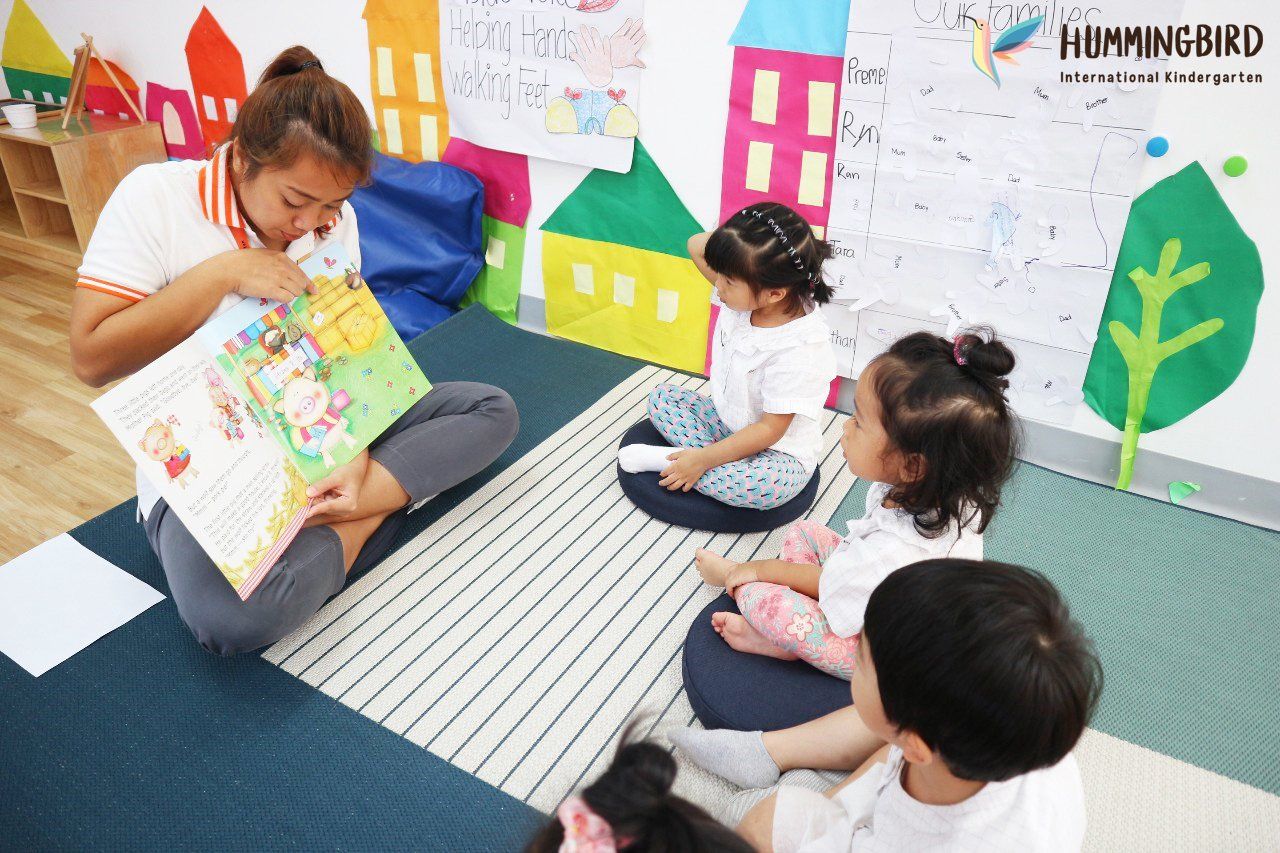 A woman is reading a book to a group of children.