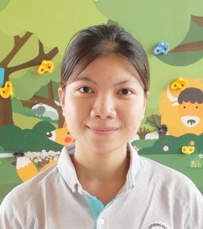 A woman is smiling in front of a wall with animals on it