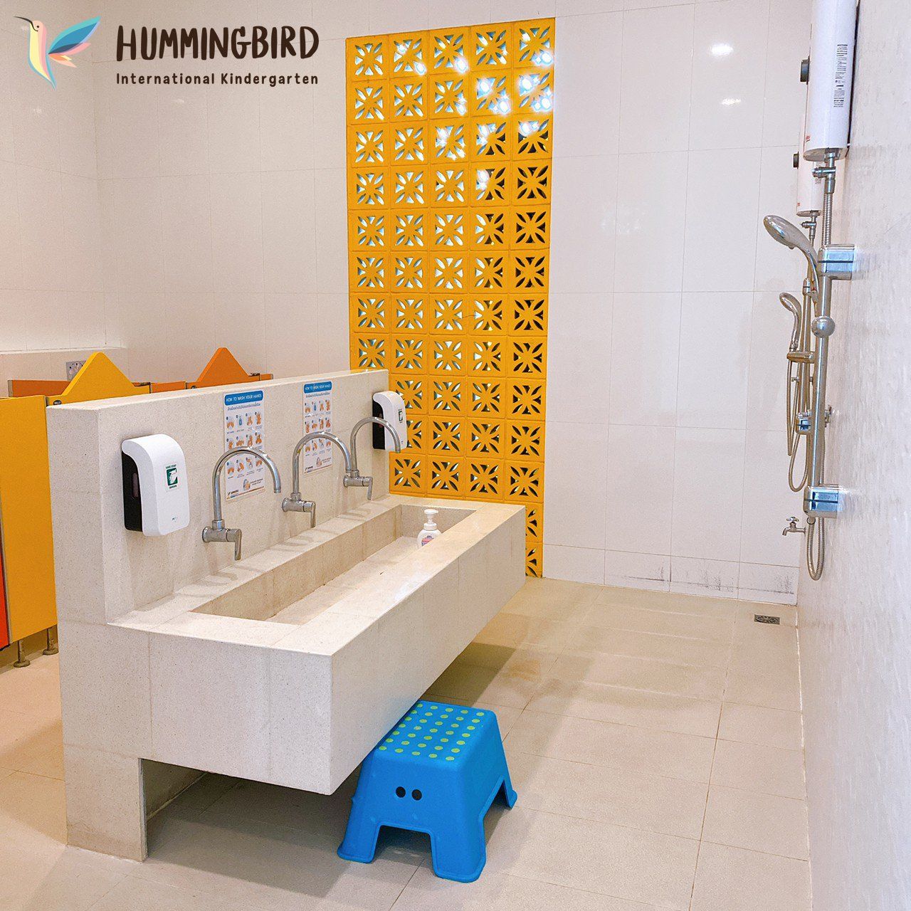 A bathroom with a hummingbird logo on the wall