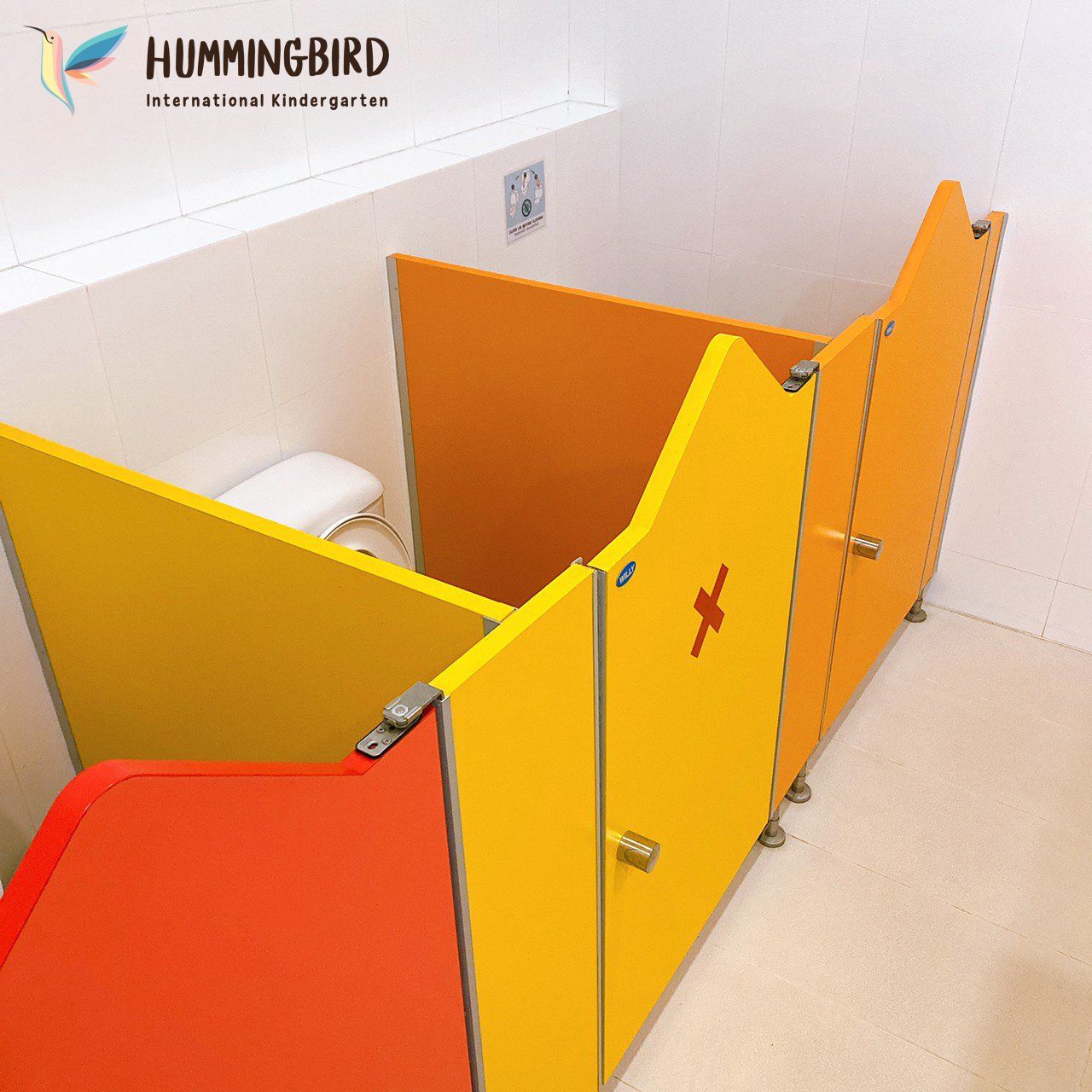 A bathroom with a hummingbird logo on the wall