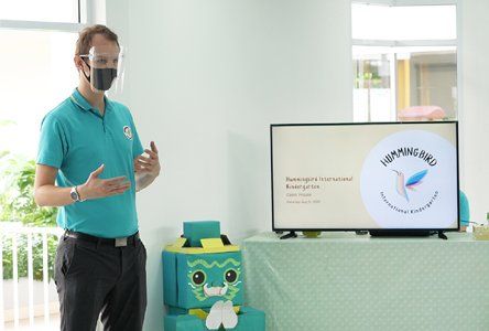 A man wearing a mask is standing in front of a television.