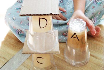 A child is holding a cup with the letter a on it