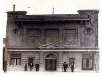 a black and white photo of a large building with people standing in front of it . Original location of W.F Gormley & Sons Funeral Chapel